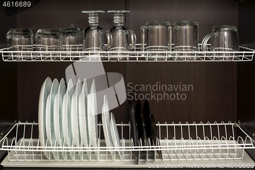 Image of Clean plates and cups are neatly located in kitchen cupboard