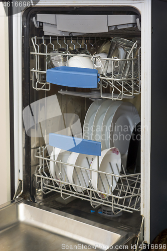 Image of Dishwasher at home kitchen with clean plates, cups, spoons and forks in it