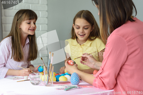 Image of Mom with two daughters paint eggs for Easter