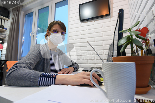 Image of A sick quarantined girl in self-isolation at home works remotely in a computer