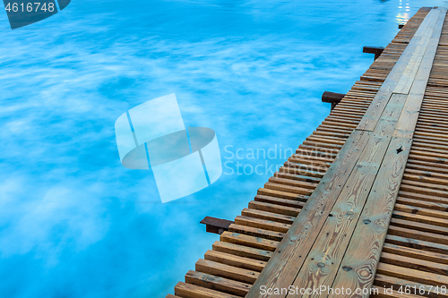 Image of The bridge goes into the distance on the right side, on the left a water surface shot with a long exposure