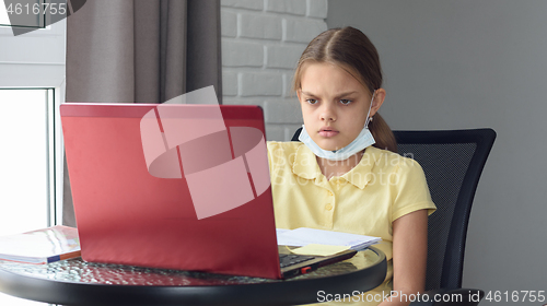 Image of Girl in self-isolation mode sits at a computer and does homework online