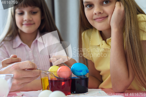 Image of Coloring Easter eggs in glasses with liquid dye, the girl looked in the frame