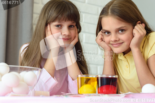 Image of Two girls are waiting for the eggs to be painted in different colors for the Easter holiday.