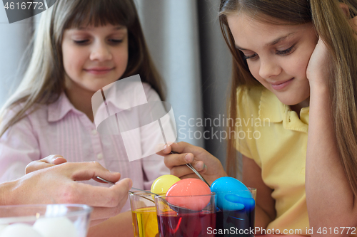 Image of Children paint chicken eggs in different colors.