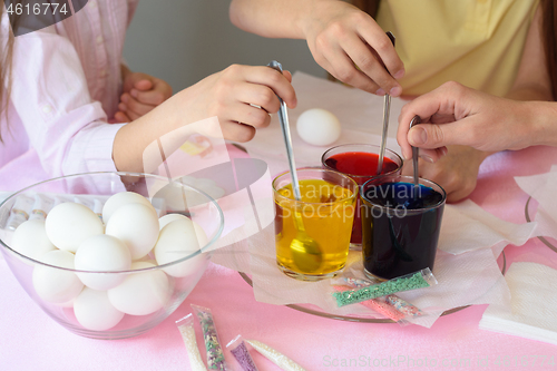 Image of Children interfere with a solution with food coloring in glasses to paint Easter eggs