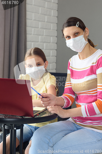 Image of Portrait of a family in front of a laptop screen in medical masks