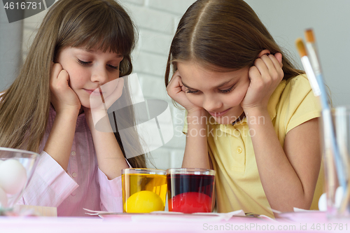 Image of Children look in glasses with liquid dye while egg staining