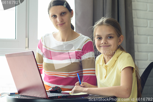 Image of Happy girl doing homework with mom looked in frame