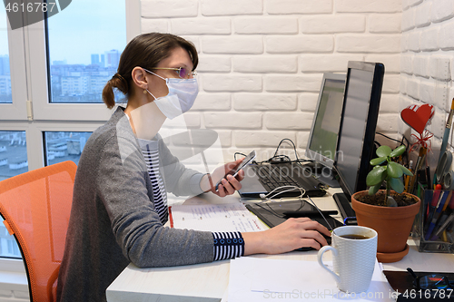 Image of A sick girl in a medical mask in self-isolation works remotely