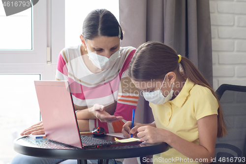 Image of The girl explains to the girl how to solve the problem correctly, in self-isolation mode in medical masks