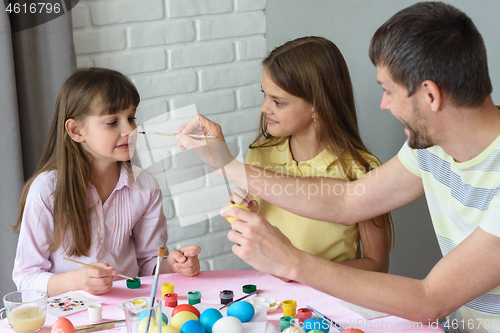 Image of Dad paints his nose for daughter while painting Easter eggs