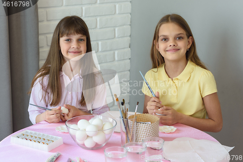 Image of Children are preparing to paint Easter eggs while sitting at a table in a home environment.