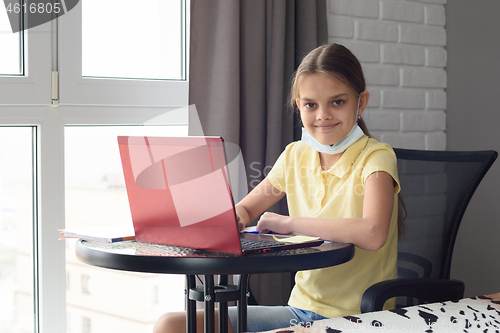 Image of Girl at home at the table doing homework online