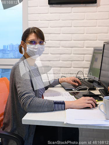 Image of The sick quarantined girl works at the computer, looked into the frame