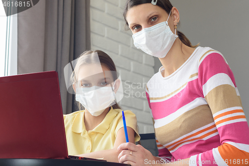 Image of Mom and daughter in medical masks quarantined study online