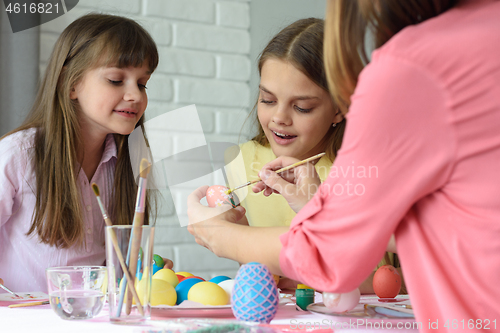 Image of Mom shows girls how to paint Easter eggs beautifully