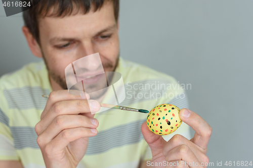 Image of Man paints an egg for Easter