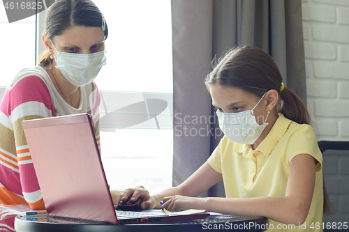 Image of Girl does homework online, mom is watching nearby