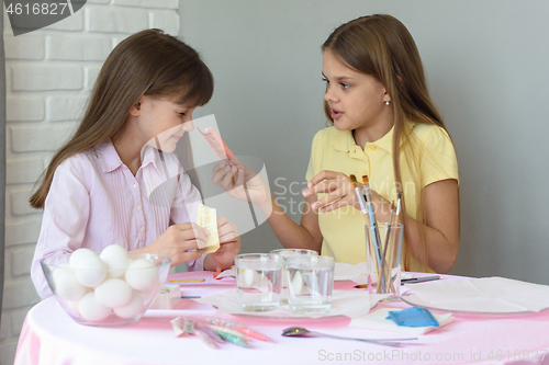 Image of A girl shows the other girl the contents of a bag of food coloring