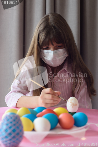 Image of Sad quarantined girl paints Easter eggs with a brush