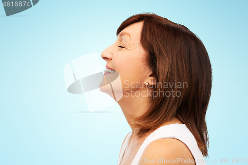 Image of profile of smiling senior woman over blue