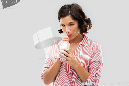 Image of woman drinking soda from can with paper straw