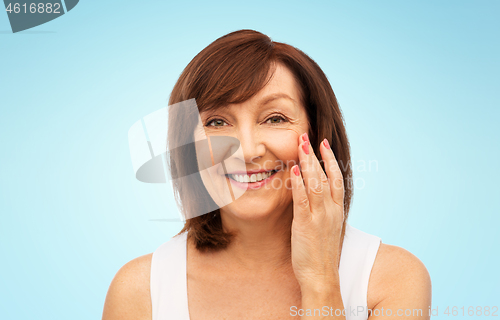 Image of portrait of smiling senior woman touching her face