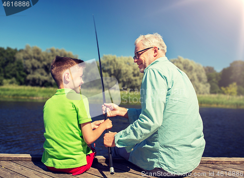 Image of grandfather and grandson fishing on river berth