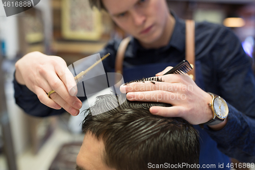 Image of male hairdresser cutting hair at barbershop