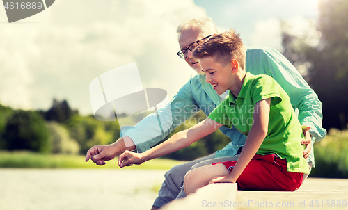 Image of grandfather and grandson sitting on river berth