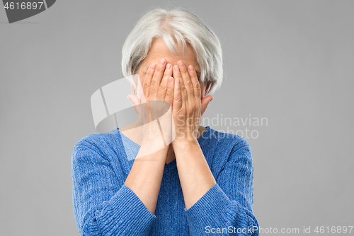 Image of stressed senior woman holding to her head