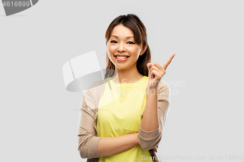 Image of happy asian woman pointing finger up