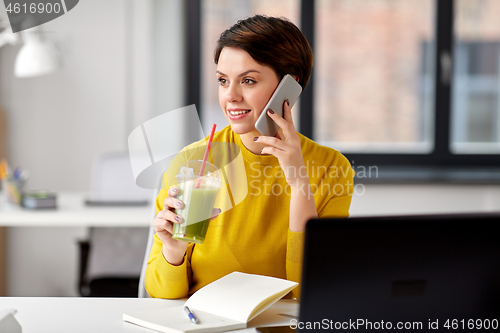 Image of woman with drink calling on smartphone at office
