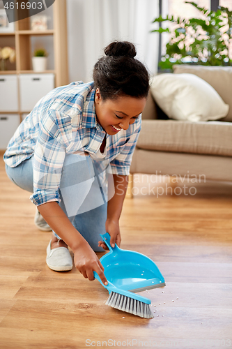 Image of happy woman with brush and dustpan sweeping floor