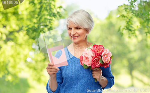 Image of happy senior woman with flowers and greeting card