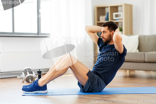 Image of man making abdominal exercises at home