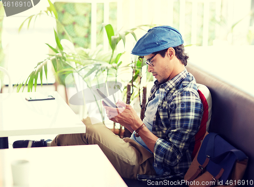 Image of man with tablet pc sitting at cafe table