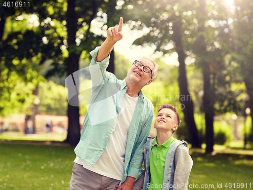 Image of grandfather and boy pointing up at summer park