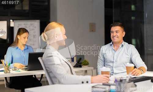 Image of business people drinking coffee at night office