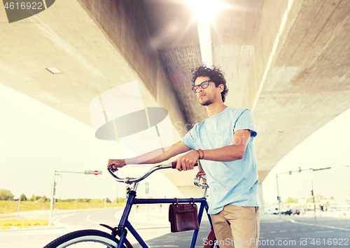 Image of hipster man with fixed gear bike under bridge