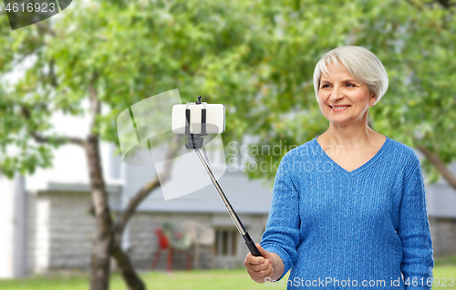 Image of smiling senior woman taking selfie by smartphone