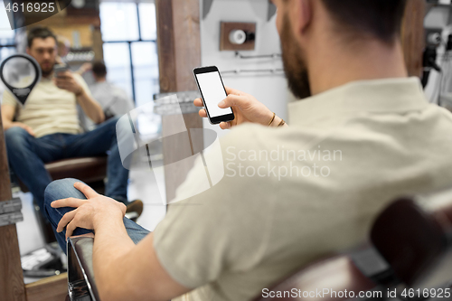 Image of close up of man with smartphone at barbershop