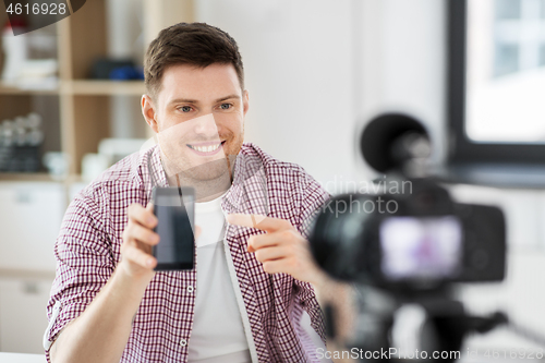 Image of male blogger with smartphone videoblogging at home