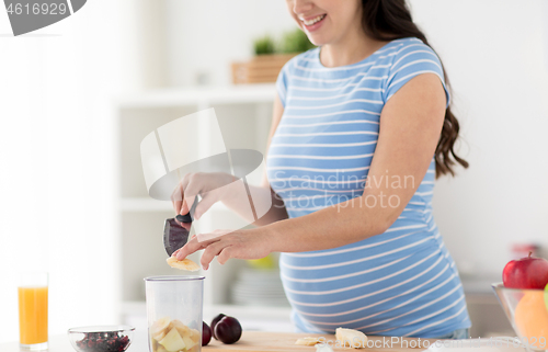 Image of pregnant woman chopping fruits at home kitchen