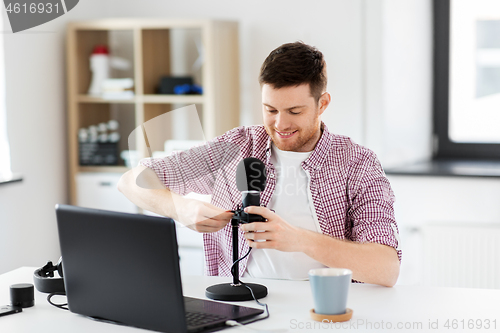 Image of male audio blogger connecting cable to microphone