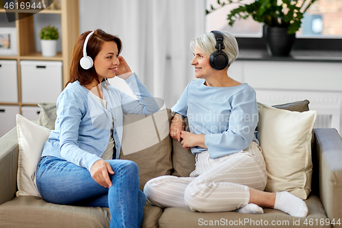 Image of senior mother and adult daughter with headphones