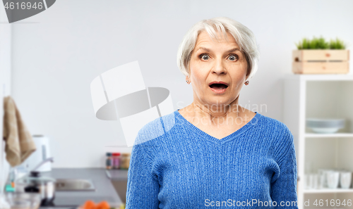 Image of shocked senior woman with open mouth at kitchen