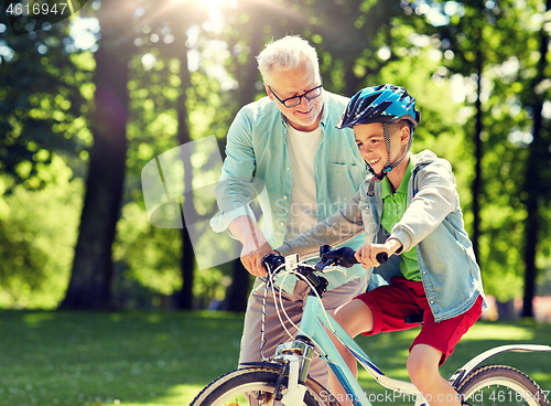 Image of grandfather and boy with bicycle at summer park