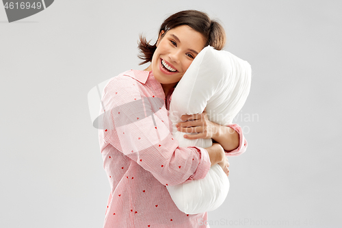 Image of happy young woman in pajama hugging pillow